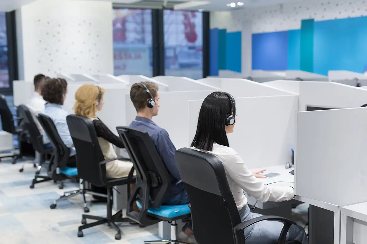 Call center team wearing headsets working at office workstations